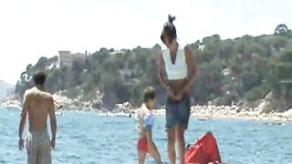 Ragazze nude giocano a frisbee sulla spiaggia