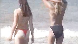 Due teen bionde camminano sulla sabbia in topless