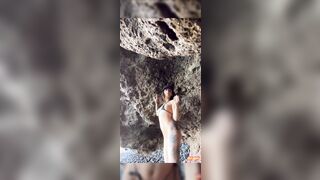 Ragazza in micro bikini tatuata strip in pubblico sugli scogli